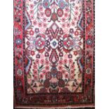 Persian runner centrally decorated with various floral bouquets upon an ivory ground with red