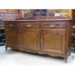 A Flemish oak dresser enclosed by three arched and field panelled doors beneath three frieze