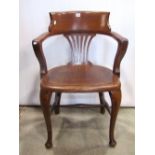 Edwardian oak bow back office chair with pierced comb splat over a solid panelled seat and