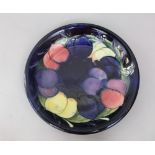 A Moorcroft blue ground plate with painted fruit and foliage decoration in yellow, green and pink,