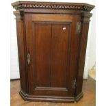 Georgian oak hanging corner cupboard, the panelled door flanked by fluted column supports and set