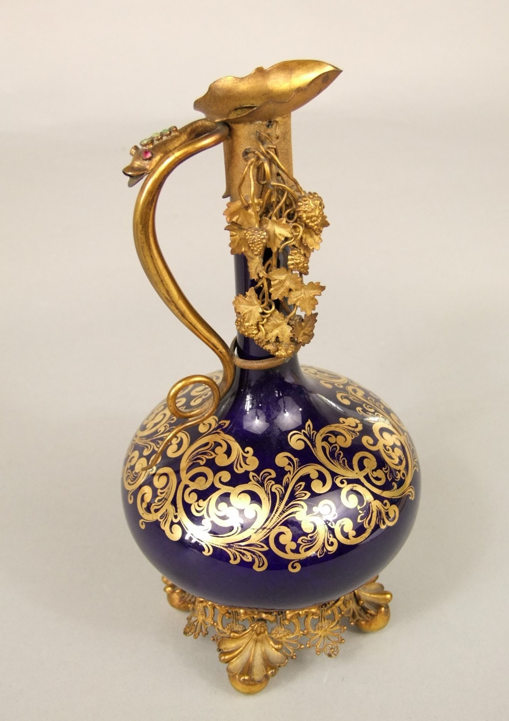 An unusual 19th century blue ground ewer with slender neck, gilded scrolling detail and ornate