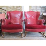 A pair of Georgian style wing armchairs with shaped outline, faux red leather upholstery and loose T
