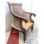 A good Regency mahogany bergere library chair, with cane work back and seat, raised on turned