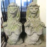 A pair of weathered cast composition stone garden ornaments or pier caps in the form of seated lions