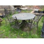 A contemporary steel framed garden table with scroll work detail beneath a circular polished granite