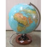 A table top illuminated globe raised on a circular teak platform base, label to reverse Scan Globe