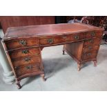 A walnut veneered kneehole twin pedestal writing desk in the Georgian style with inset leather