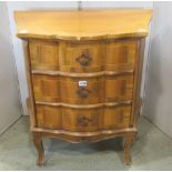 A small shaped walnut chest of three drawers with crossbanded detail raised on shaped and carved
