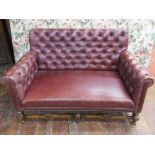 An Edwardian button back two seat sofa upholstered in brown leather raised on a turned showwood