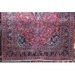 Hammadan village rug with central lobed navy blue medallion upon a red ground with running blue