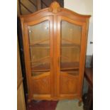 A medium to light oak free standing side cabinet enclosed by a pair of partially glazed and panelled