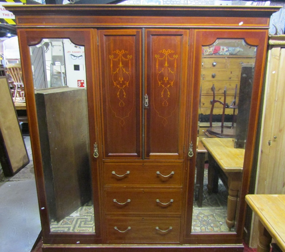 An inlaid Edwardian mahogany triple compactum wardrobe, the central section fitted with three long