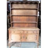 An Edwardian/1920s stripped oak dresser, fitted with two frieze drawers, over moulded panelled