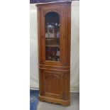 A contemporary reproduction stripped pine floorstanding corner cabinet enclosed by two doors, the