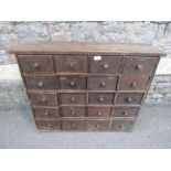 A vintage stained pine nest of twenty small drawers, with metal button knob handles, 86cm wide x