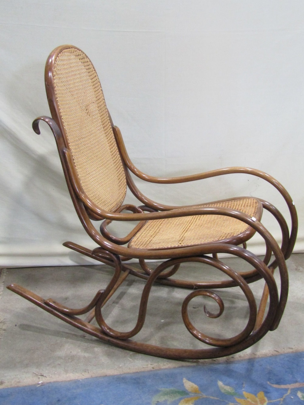 A vintage bentwood rocking chair, with scrolled frame and cane panel seat and back (unmarked but