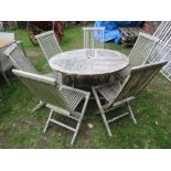 A weathered teak garden table of circular form with segmented slatted top, raised on folding X