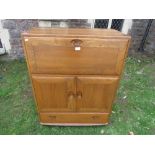 An Ercol blonde elm side cabinet, with fall flap over two doors and long drawer, with dished handles