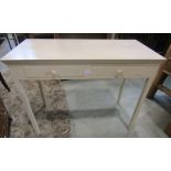 A cream painted side table with two frieze drawers raised on square cut supports, together with a