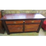 A low hardwood side cupboard enclosed by a pair of horizontal slatted panelled doors beneath two