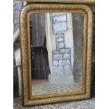 A late 19th century wall mirror, the moulded and gilded arched frame with repeating foliate