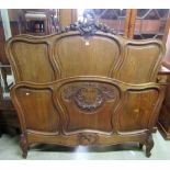 An oak double bedstead, the panelled head and foot board within a shaped carved and moulded frame