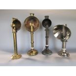 A collection of four various brass candle lamps with hoods two in brass, one in copper, one in