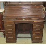 An oak kneehole twin pedestal roll top desk, the S shaped tambour roll enclosing a pigeon holed
