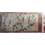 A Chinese wool prayer mat size rug decorated with birds on branches upon an ivory ground, 130 x 60