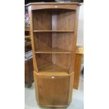 An Ercol blonde elm freestanding corner cupboard the lower section enclosed by a rectangular door