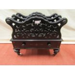 A Victorian ebonised two divisional Canterbury with carved and pierced detail over a frieze drawer