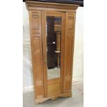 An Edwardian ashwood single wardrobe enclosed by a full length central door with bevelled edge