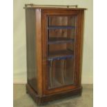 A Victorian walnut music cabinet enclosed by a rectangular glazed panelled door revealing a