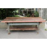 An industrial steel and wooden framed work bench, with painted angular supports, united by a boarded