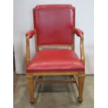 A light oak framed open elbow chair, with red faux leather upholstered seat, back and arm rests,