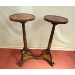 A pair of walnut torcheres, the circular tops raised on turned and tapering columns with tripod