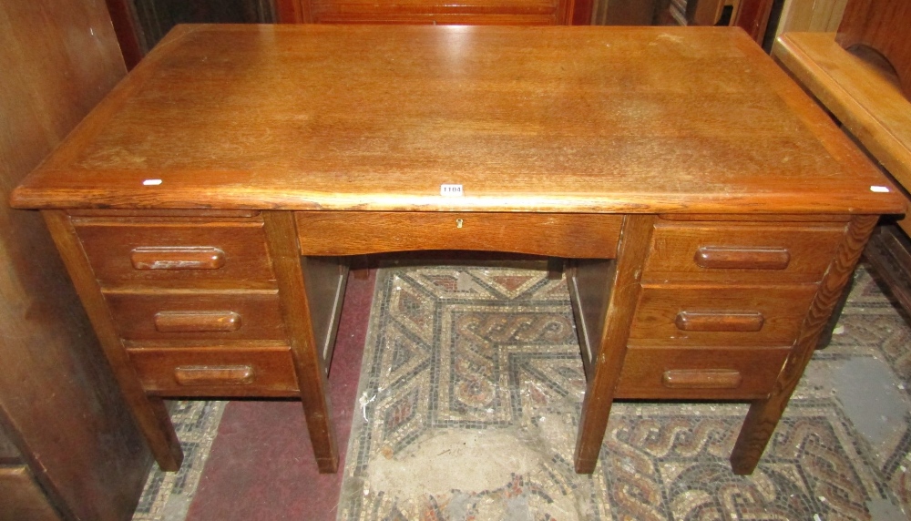 A vintage oak kneehole desk fitted with an arrangement of six drawers disguised as seven, with