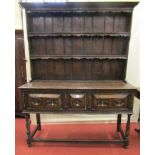 An oak dresser in the Jacobean manner, enclosed by three panelled drawers with applied geometric