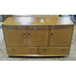 An Ercol blonde elm low sideboard, enclosed by three doors over two drawers, with dished handles,