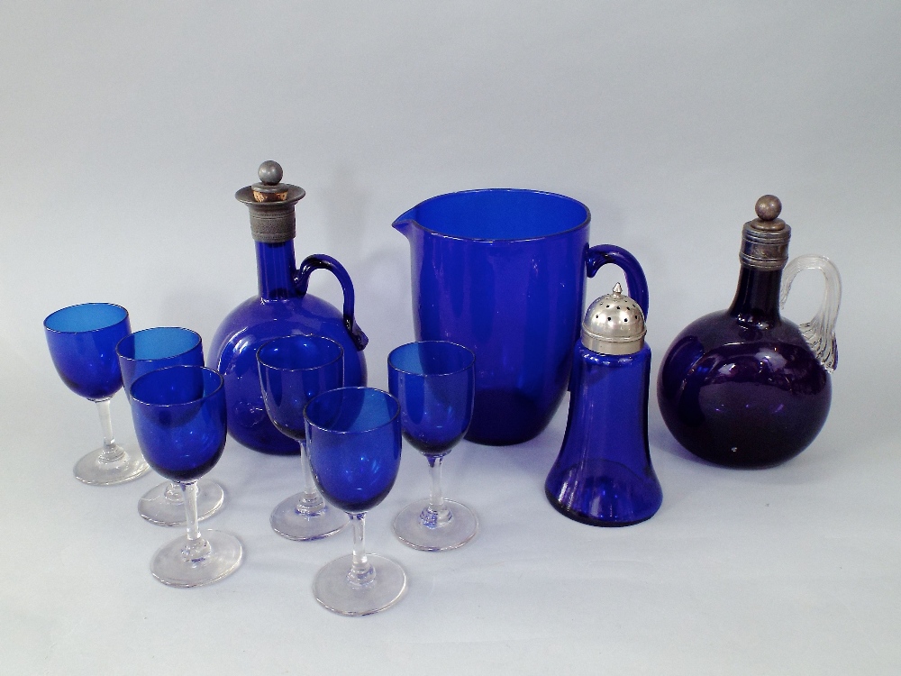 Two similar blue and amethyst glass wine flasks with white metal collars and stoppers together