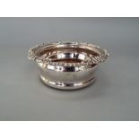 Silver plated deep wine coaster with turned wooden base with inset silver plated crest of an arm