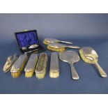 A box containing a collection of silver dressing set items comprising seven brushes, a hand mirror