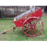 A vintage wooden hand cart with iron fittings, two spoke wheels with iron rims and red painted