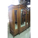 An oak armoire with arched and moulded cornice and carved floral pediment over a shallow