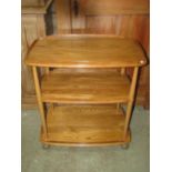 An Ercol blonde elm and beechwood three tier tea trolley of rectangular form with moulded outline