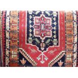 Persian full pile rug with central navy blue medallion upon a red ground, 160 x 100 cm