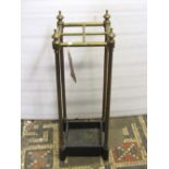 A brass four divisional umbrella/stick stand, with tubular rails, turned finials and cast iron