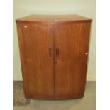 A "Turnidge" retro teak drinks cabinet/bar, the bow front enclosed by two full length doors with