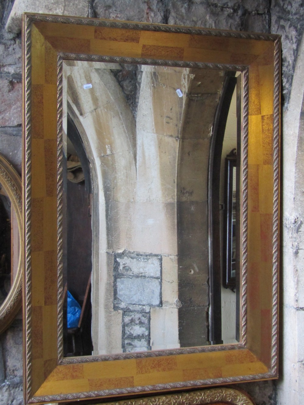 A contemporary gilt framed wall mirror of rectangular form with bevelled edge plate and foliate